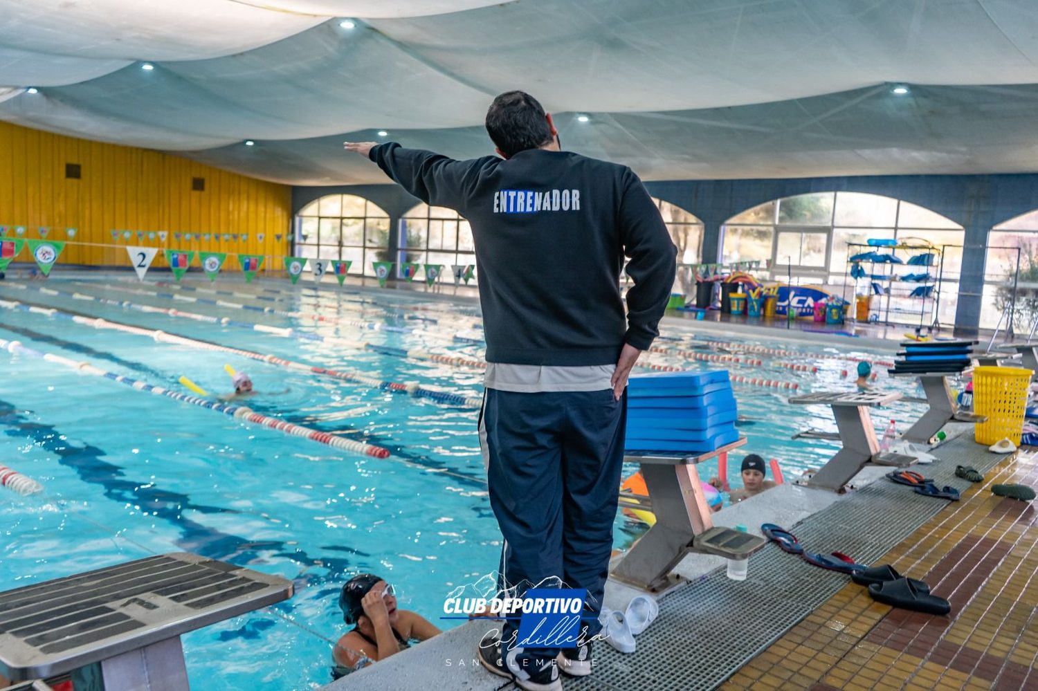 Piscina temperada de la UCM con un entrenador junto al borde durante una clase